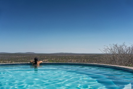 Young girl in the pool overlooking the Nambian savannah. Africa.の写真素材