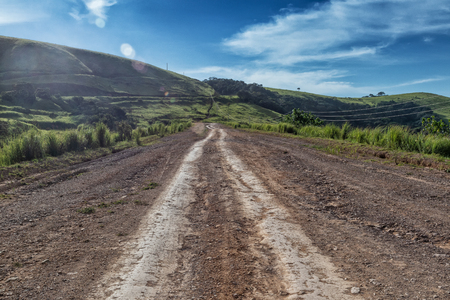Mud road with tire marks runs through green valley in Malanje. Angola. Africa.の写真素材