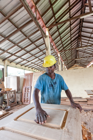 CABINDA/ANGOLA - 08JUN2010 - African carpenter making a door in a carpentry factory.のeditorial素材