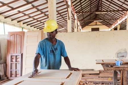 CABINDA/ANGOLA - 08JUN2010 - African carpenter making a door in a carpentry factory.のeditorial素材