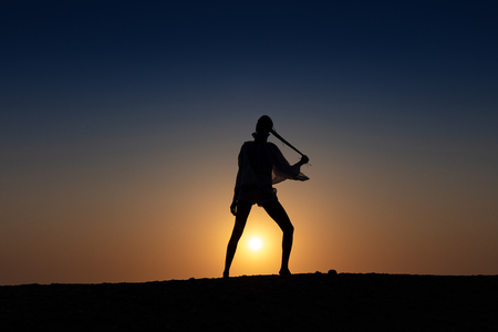 Silhouette of African girl on hill top posing and dancing with sunset view and ocean view.の写真素材
