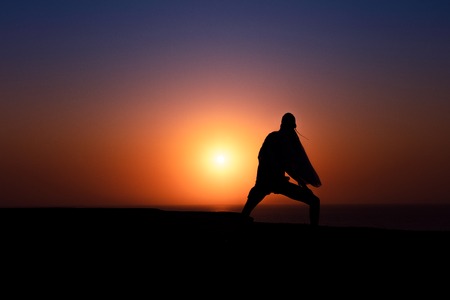 Silhouette of African girl on hill top posing and dancing with sunset view and ocean view.の写真素材