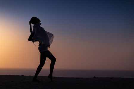 Silhouette of African girl on hill top posing and dancing with sunset view and ocean view.の写真素材