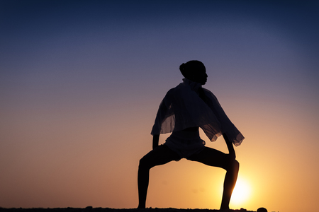 Silhouette of African girl on hill top posing and dancing with sunset view and ocean view.の写真素材