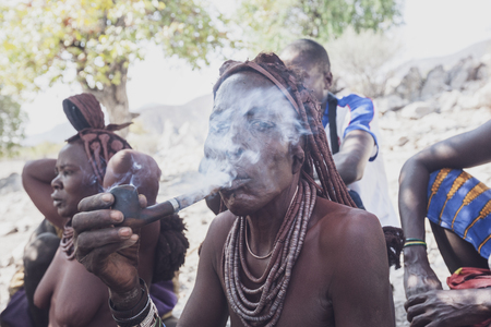 NAMIBE/ANGOLA - 28 AUG 2013 - Portrait of African elderly woman belonging to a tribe smoking with pipe.のeditorial素材