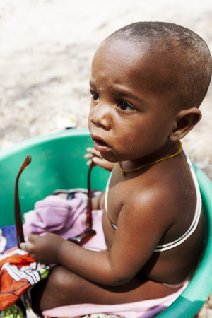 NAMIBE/ANGOLA - 28 AUG 2013 - African baby tribe playing with sunglasses.のeditorial素材