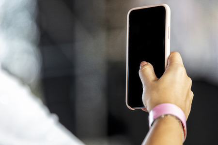 Woman hand holding on mobile phone with blurred background.の写真素材