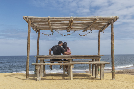 NAMIBE/ANGOLA 02NOV2018 - Couple sitting on wooden porch overlooking the sea.のeditorial素材