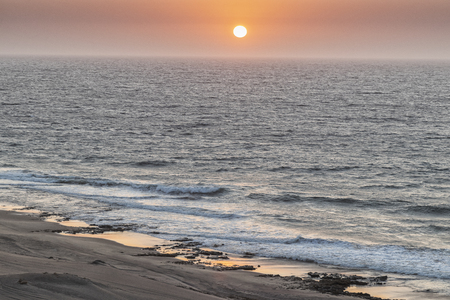 Beautiful sunset on the wild Namibe beach with canyons and desert.の写真素材