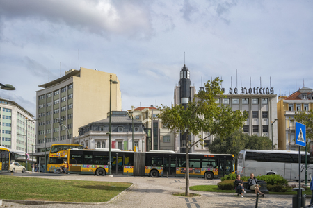 LISBON/PORTUGAL 21OCT2018 - Junction of the well-known Portuguese area MarquÃªs de Pombal with bus and tourists sitting on a bench.の写真素材