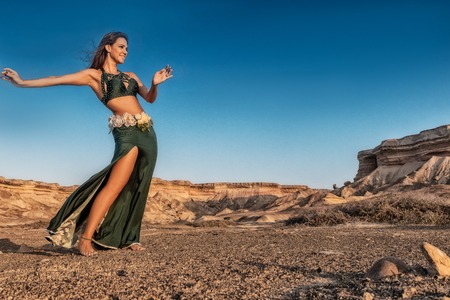 Woman dancing to the famous belly dance with natural sunset light, in the Namibe Desert with canyons. Africa. Angola.の写真素材