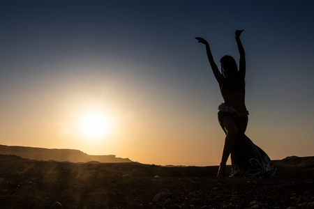 Woman dancing to the famous Arab belly dance. With sunset in the arid desert plain of Namibe. Africa. Angola.の写真素材