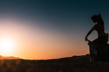 Woman dancing to the famous Arab belly dance. With sunset in the arid desert plain of Namibe. Africa. Angola.の写真素材