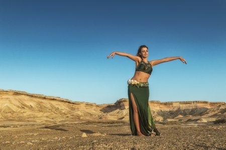 Woman dancing to the famous belly dance with natural sunset light, in the Namibe Desert with canyons. Africa. Angola.の写真素材
