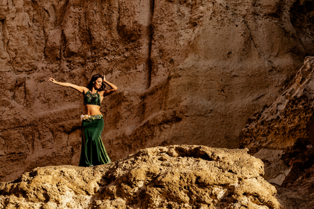 Young girl in green dress dancing the famous belly dance, in the mythical space of the canyons of the Namibe desert. Africa. Angola.の写真素材