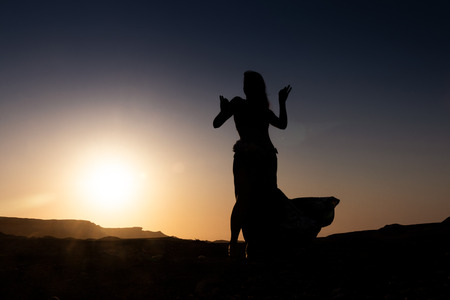 Woman dancing to the famous Arab belly dance. With sunset in the arid desert plain of Namibe. Africa. Angola.の写真素材