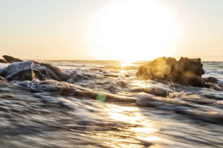 Beautiful sunset on the deserted Namibe beach. Photograph taken by the water with cliff and rocks. Africa. Angola.の写真素材