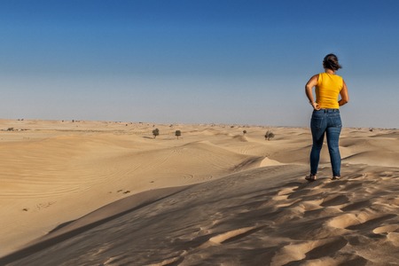 Photograph of woman on top of a dune in the desert of Abu Dhabi. UAEの写真素材