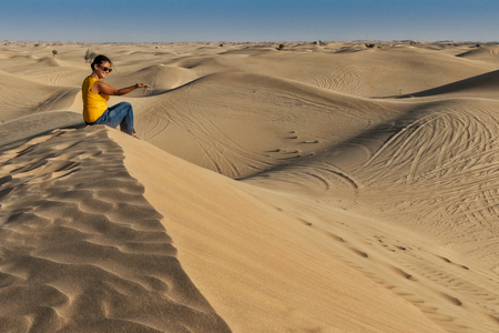 UAE/ABUDHABI - 13 DEZ 2018 - Photograph of woman sitting on top of a Dune in the desert of Abu Dhabi. UAEのeditorial素材