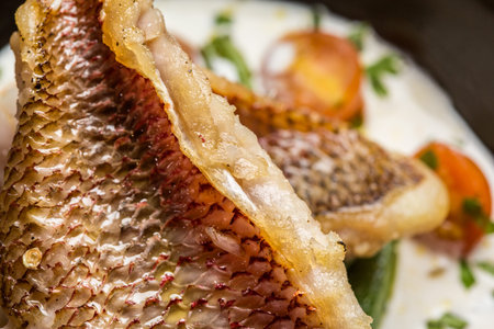 Fried fish accompanied by keabos and tomatoes seen from above. Gourmet dish.