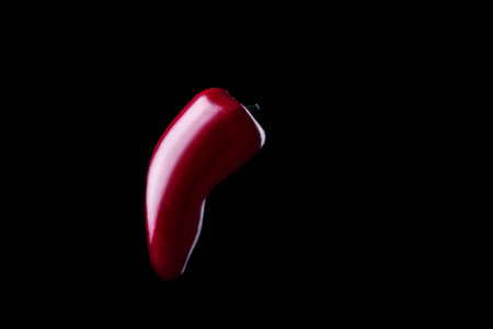 Large and red hot chilli isolated on black background.