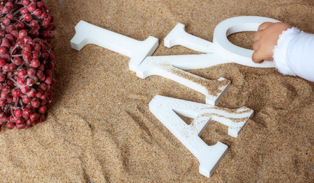 Baby hand moving letters in sand background.の写真素材