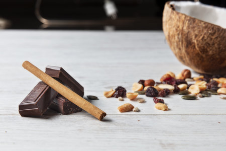 squares of chocolate with nuts, coconut and cinnamon on wooden table.の写真素材