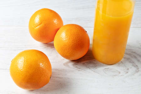 bottle of natural orange juice with oranges on wooden table.の写真素材