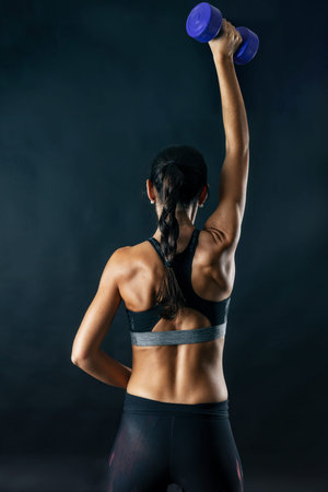 Woman performing fitness exercises isolated on dark background.の写真素材