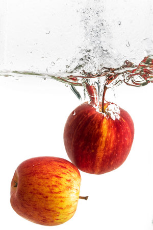 Splash of water with red apple and white background.の写真素材