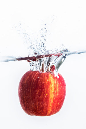 Splash of water with red apple and white background.の写真素材
