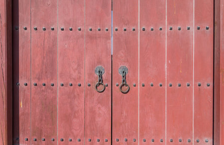 Red old wooden door or gate with metal door ring handle knocker