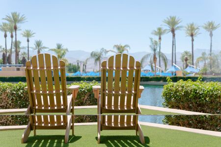Wooden two chairs by the pool with green artificial grass.の写真素材