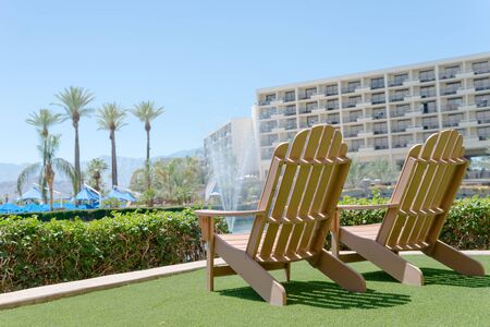 Wooden two chairs by the pool with green artificial grass.の写真素材