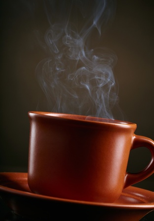 Cup of coffee with smoke over dark backgroundの写真素材