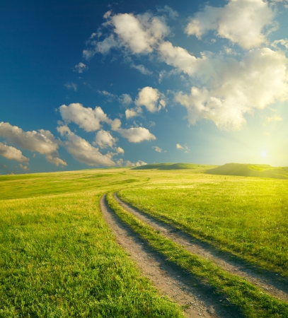 Summer landscape with green grass, road and cloudsの写真素材