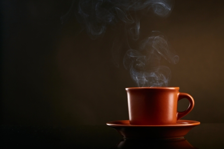 Cup of coffee with smoke over dark backgroundの写真素材
