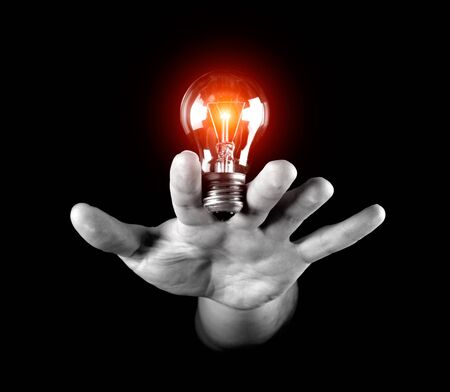 Hand holding light bulb isolated on black
の写真素材