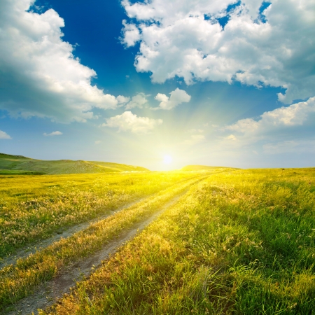 Summer landscape with green grass, road and cloudsの写真素材