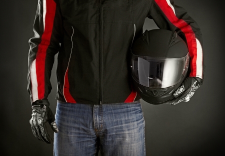 Biker with helmet in his hands. Dark backgroundの写真素材