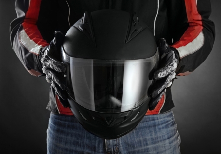 Motorcyclist with helmet in his hands. Dark backgroundの写真素材