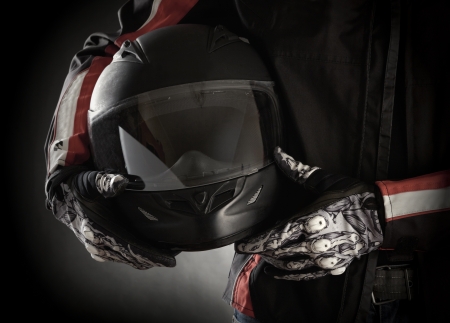 Motorcyclist with helmet in his hands. Dark backgroundの写真素材