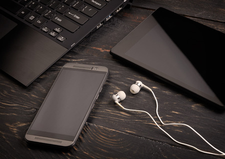 Laptop, smart phone, tablet pc and headset on wooden backgroundの写真素材