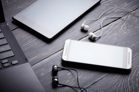 Laptop, smart phone, tablet pc and headset on wooden backgroundの写真素材