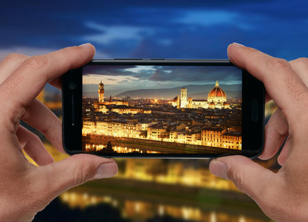 Travel concept. Hands taking photo of night city with smartphone camera. Florence, Italy.の写真素材