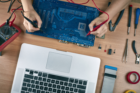 Technical repairs motherboard in service center. Laptop, tester, CPU and tools. Computer repair concept. Top viewの写真素材