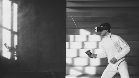 Concentrated fencer man practice fencing exercises using VR headset and training simulator...