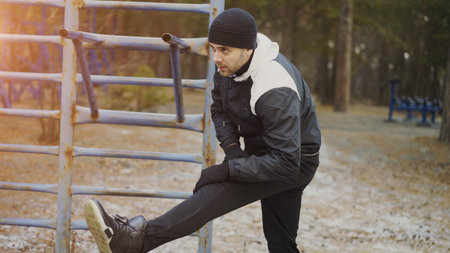 Attractive man runner doing stretching exercise preparing for morning workout and jogging in winter...