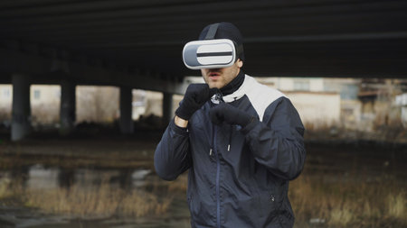 Martial boxing man in VR 360 headset training punches in virtual reality fight at urban location...