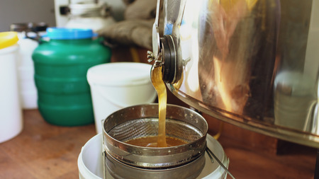 Closeup of honey flowing off harvesting beekeper equipment in apiaryの写真素材